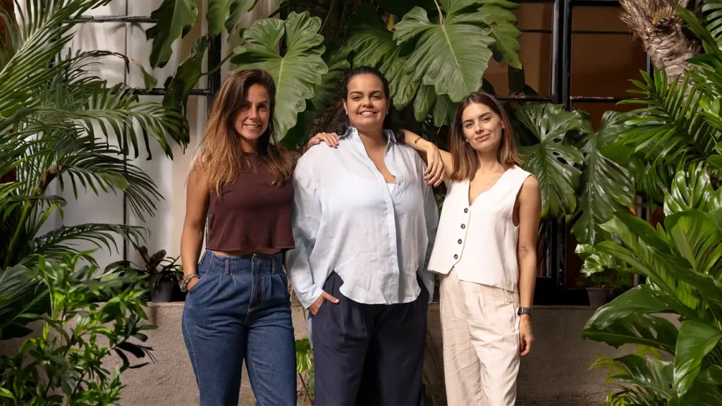 Carol Barcellos posa ao lado de equipe da Agência Supernova Sports em ambiente com plantas