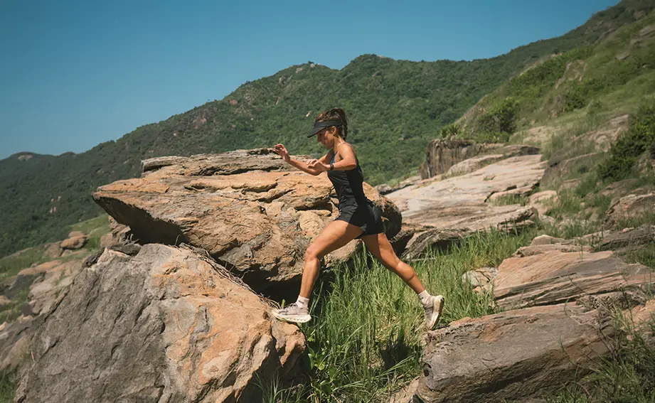 Carol Barcellos em treino outdoor entre pedras e trilha na natureza